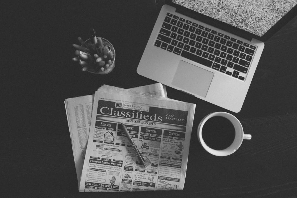pexels-photo-265642 A black and white image of a laptop, newspaper, and coffee cup on a desk.